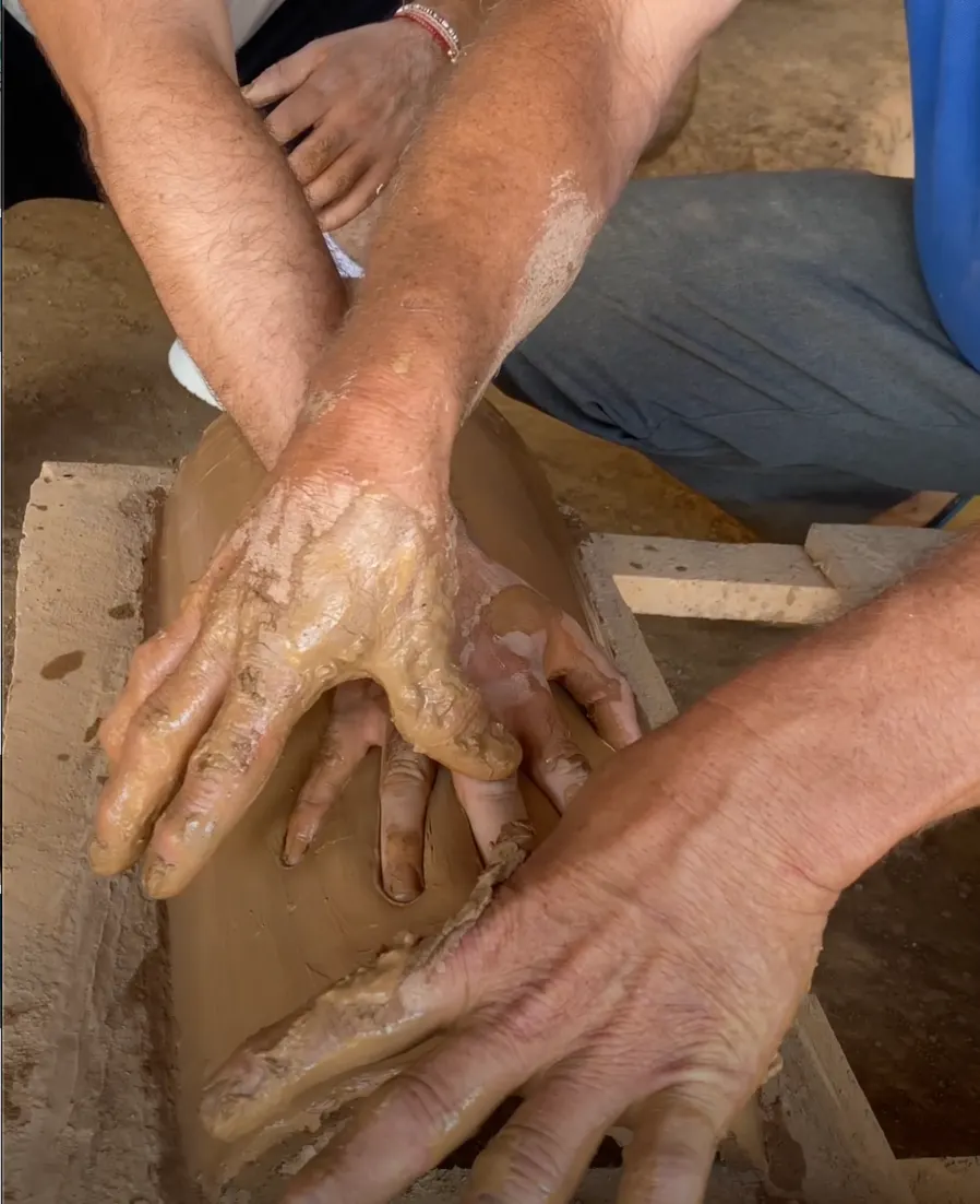 Manos moldeando una teja de barro en el taller de Barichara