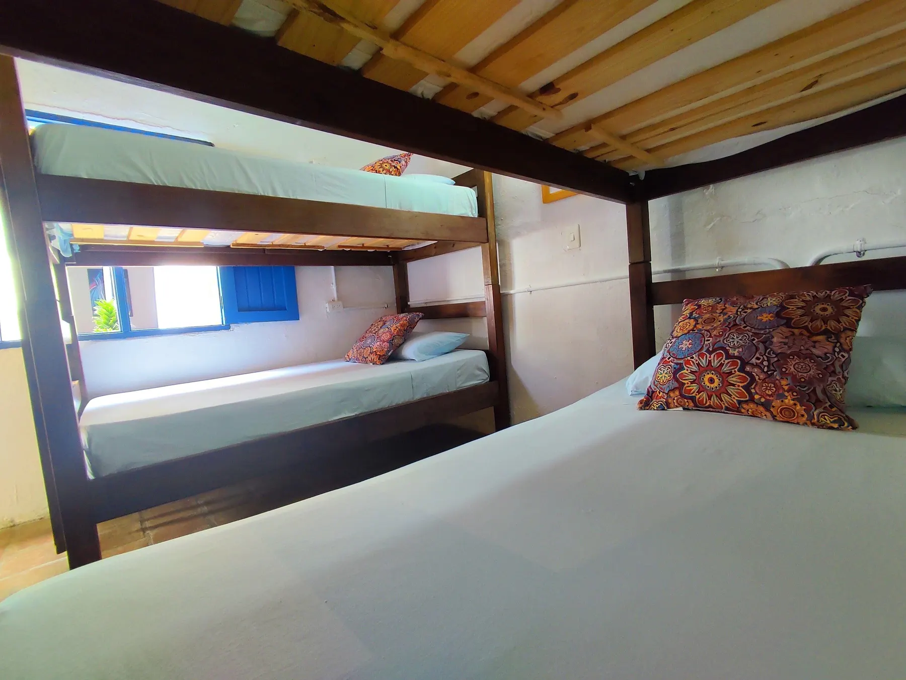 Litera de madera sobre cama doble en el dormitorio de Trip Monkey Barichara
