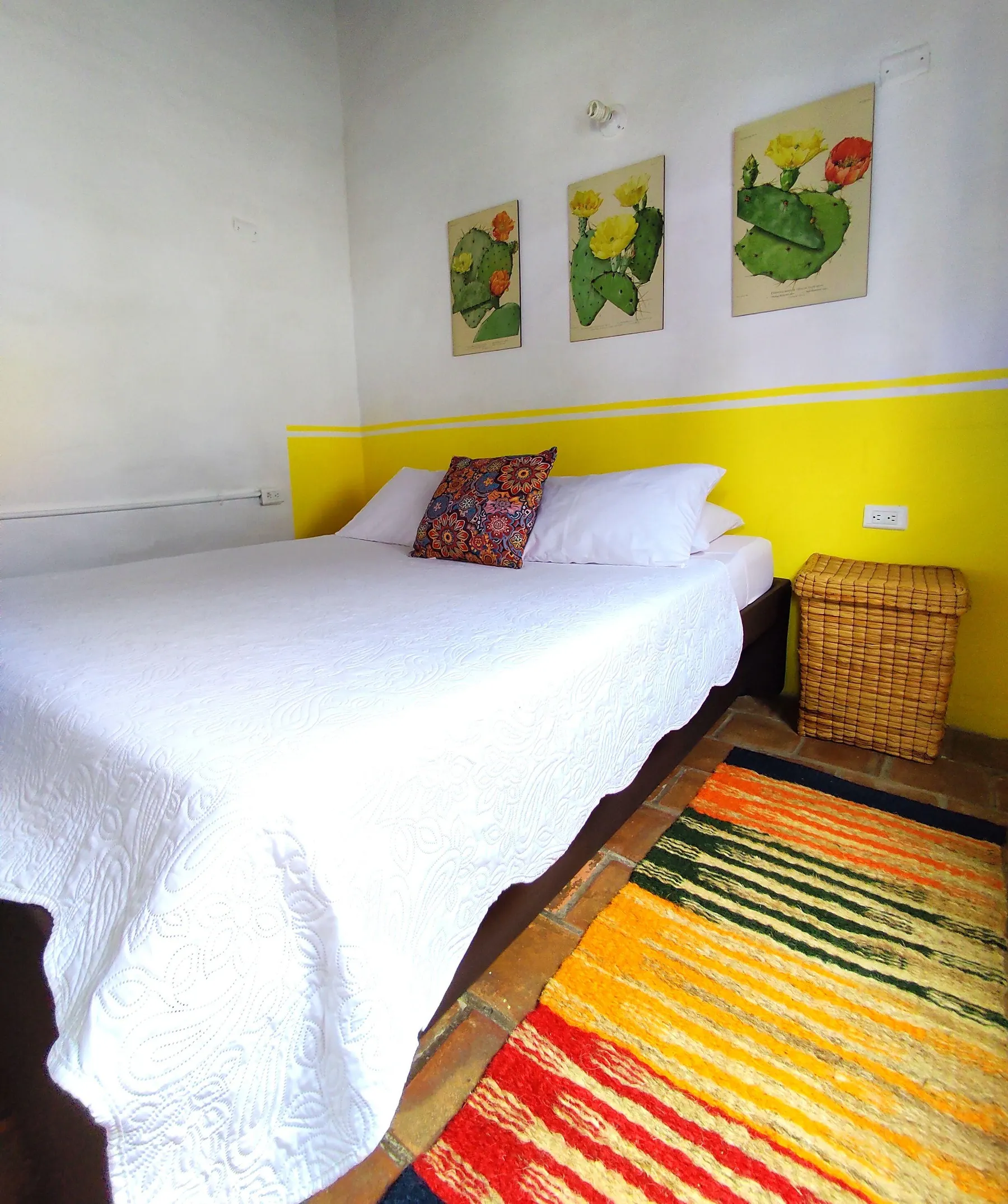 Habitación Doble de Trip Monkey Barichara con canasto y tapete de colores