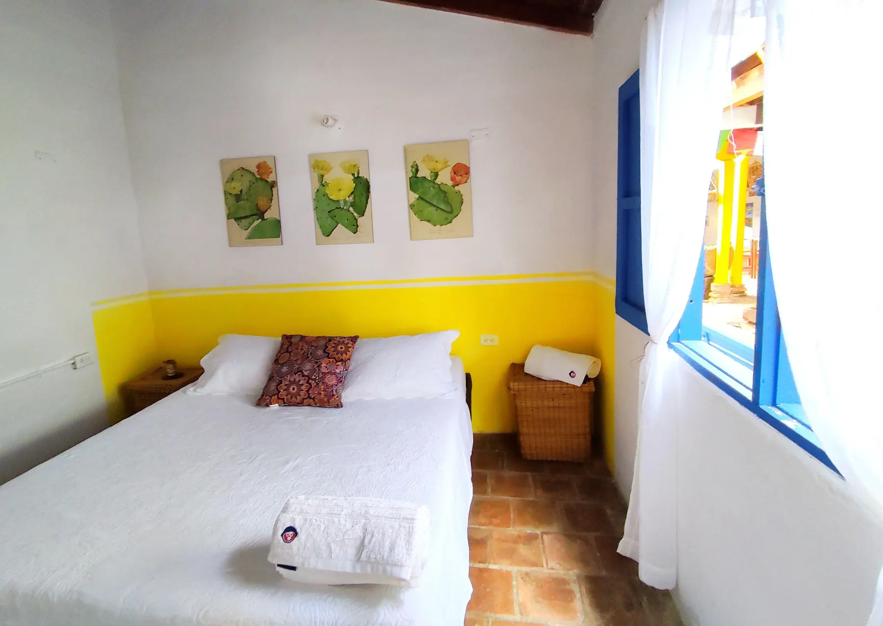 Habitación Doble de Trip Monkey Barichara con franja amarilla y mesa de noche