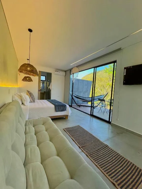 Sofá y cama del Glamping Deluxe, con luz cálida y terraza al fondo