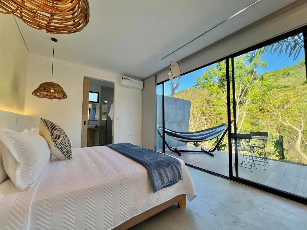 Glamping Deluxe: cama doble grande frente al ventanal, con hamaca en la terraza, en Glamping Del Río by Trip Monkey