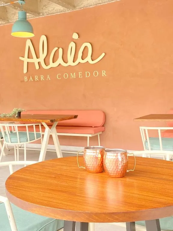 Letrero de Alaia Barra Comedor con mesas y vasos de cobre