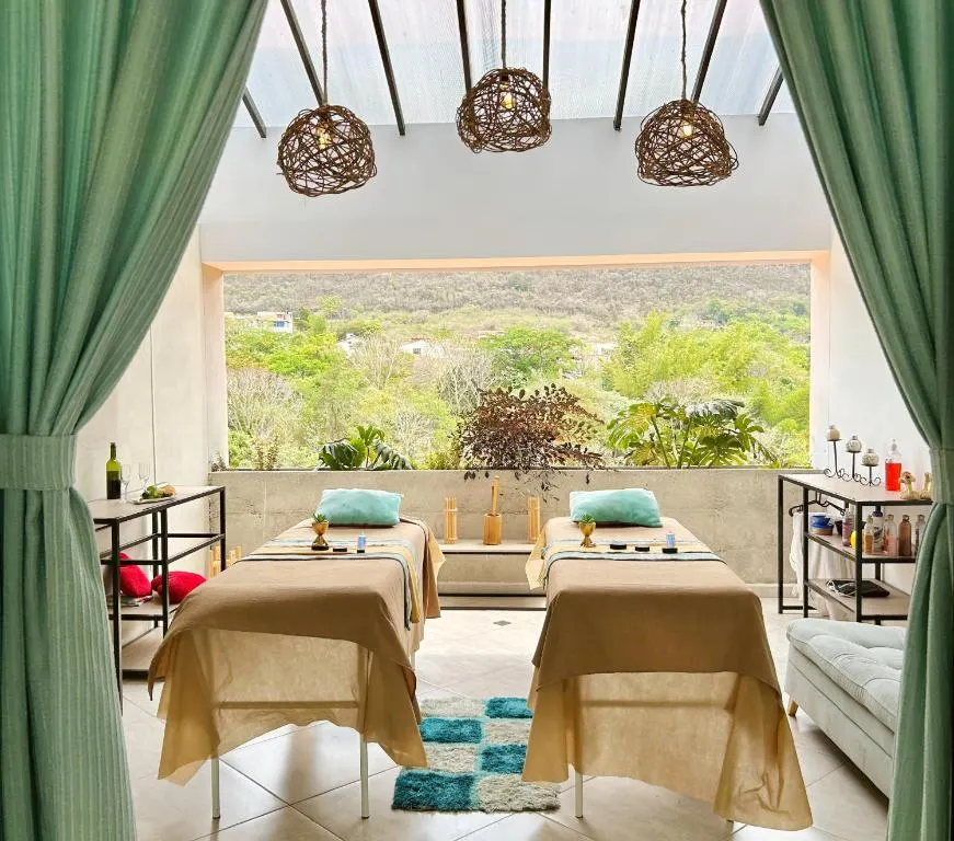 Sala de masajes del spa con dos camillas y vista al bosque