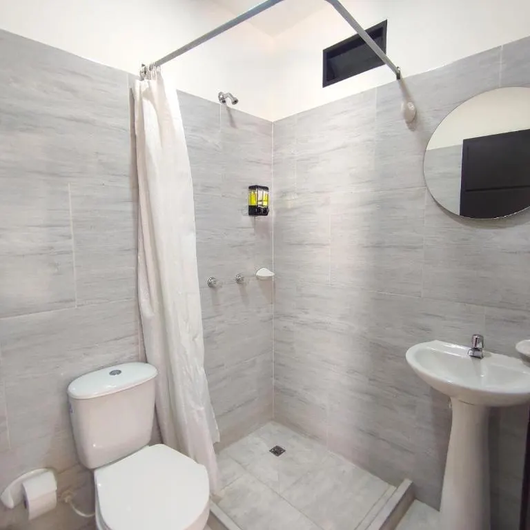 Baño privado con ducha y espejo redondo en Trip Monkey Origen