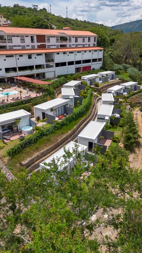 Unidades de glamping con jacuzzi en terrazas de piedra, con el edificio de Trip Monkey Del Río y la montaña al fondo