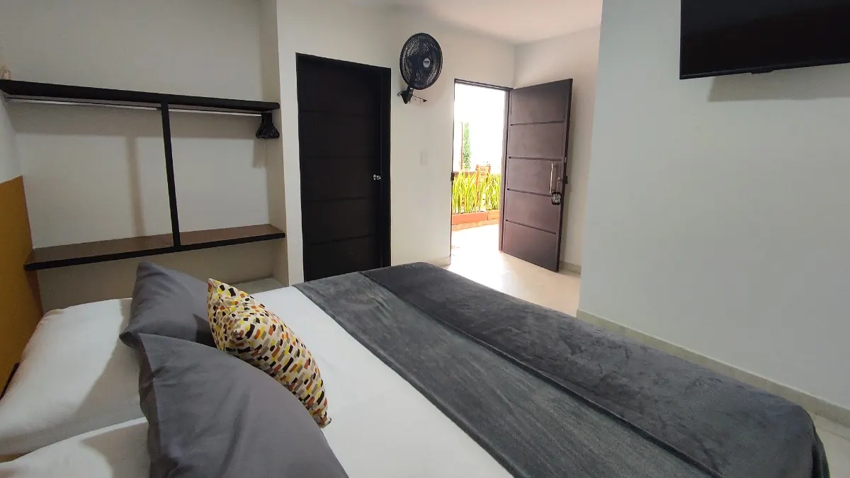 Habitación Doble con cama queen, televisor y ventilador en Trip Monkey Origen